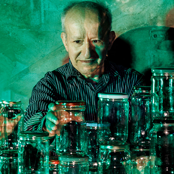 a man standing behind a collection of jars and holding one