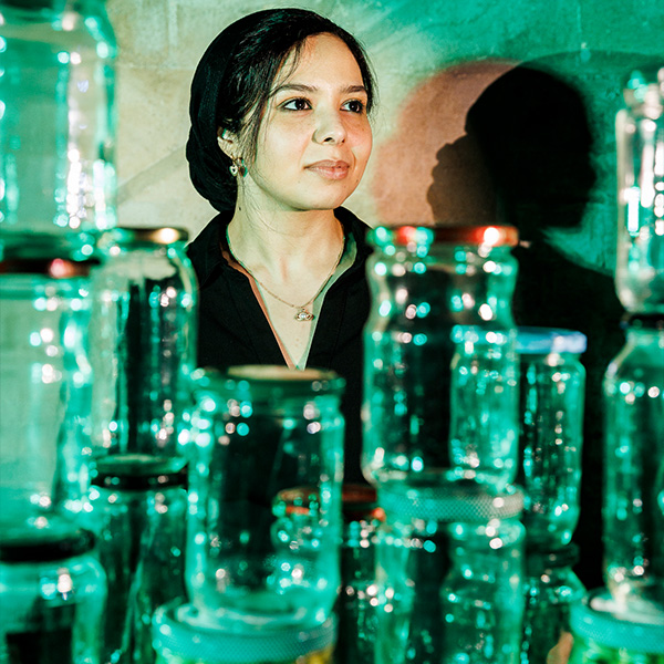 a woman standing behind a collection of glass jars